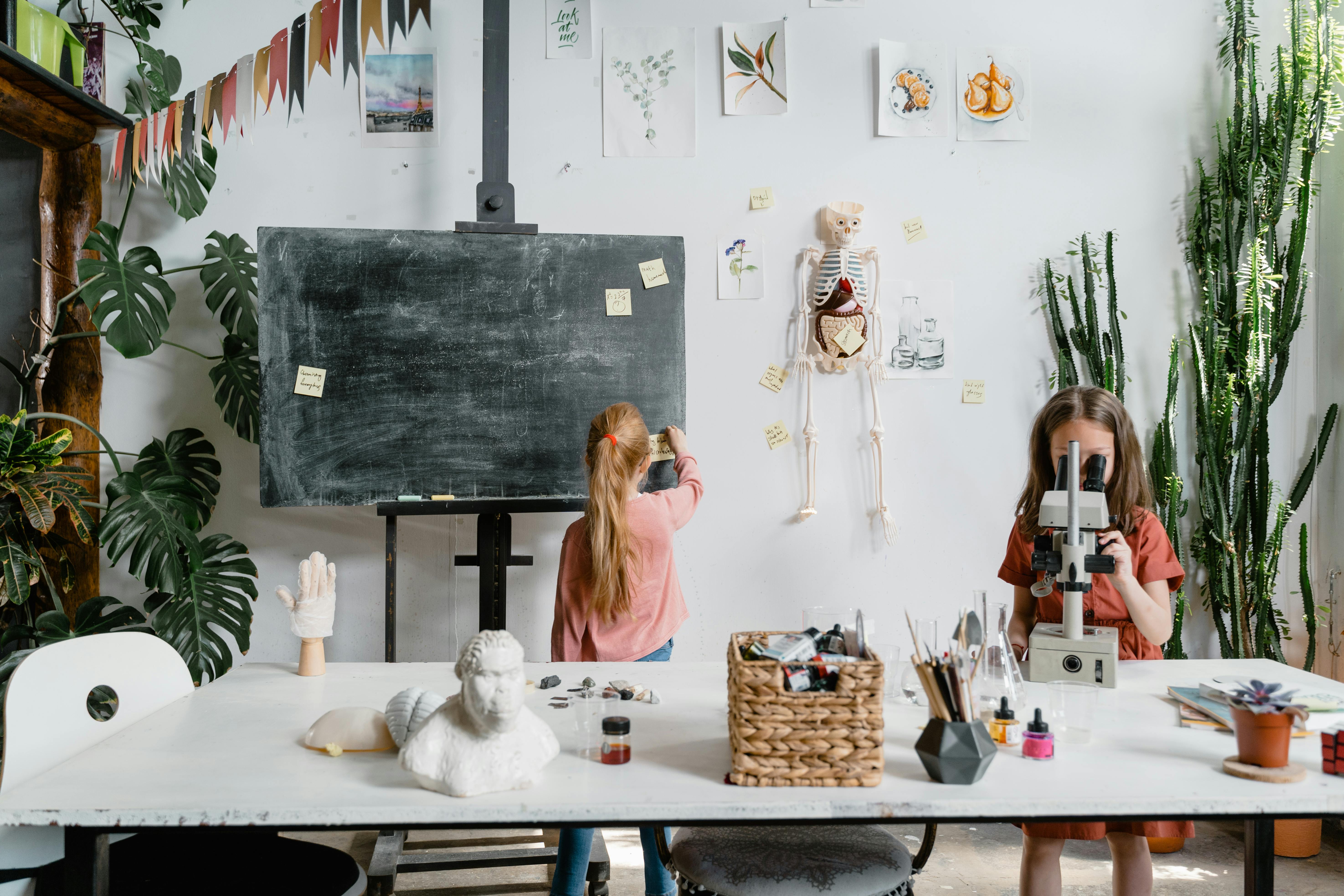Young girls exploring science with a microscope in an interactive classroom setting.