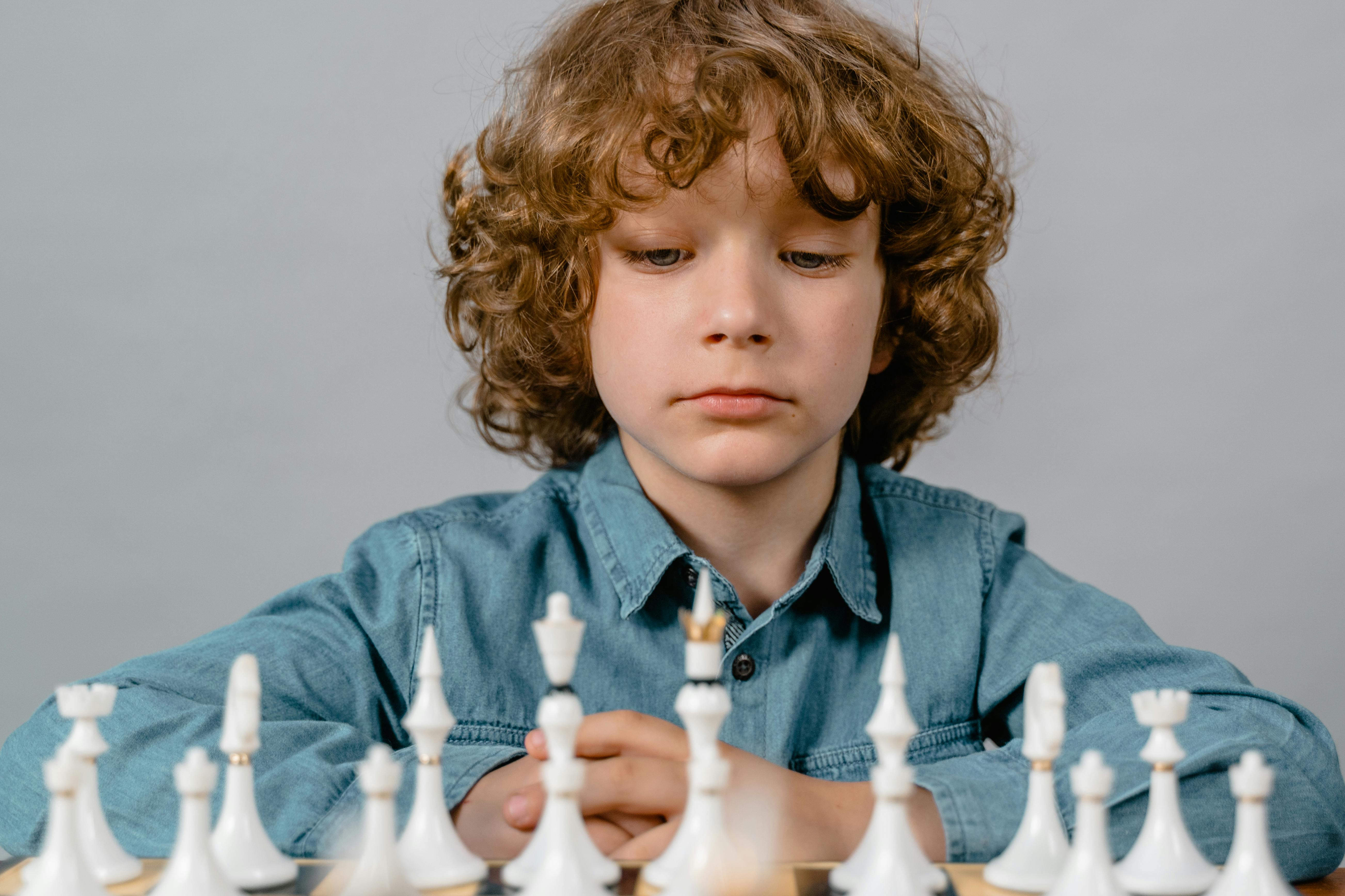 Premium Photo  Portrait of child during chess game boy plays chess and  thinks intently about the next move isolation on white background