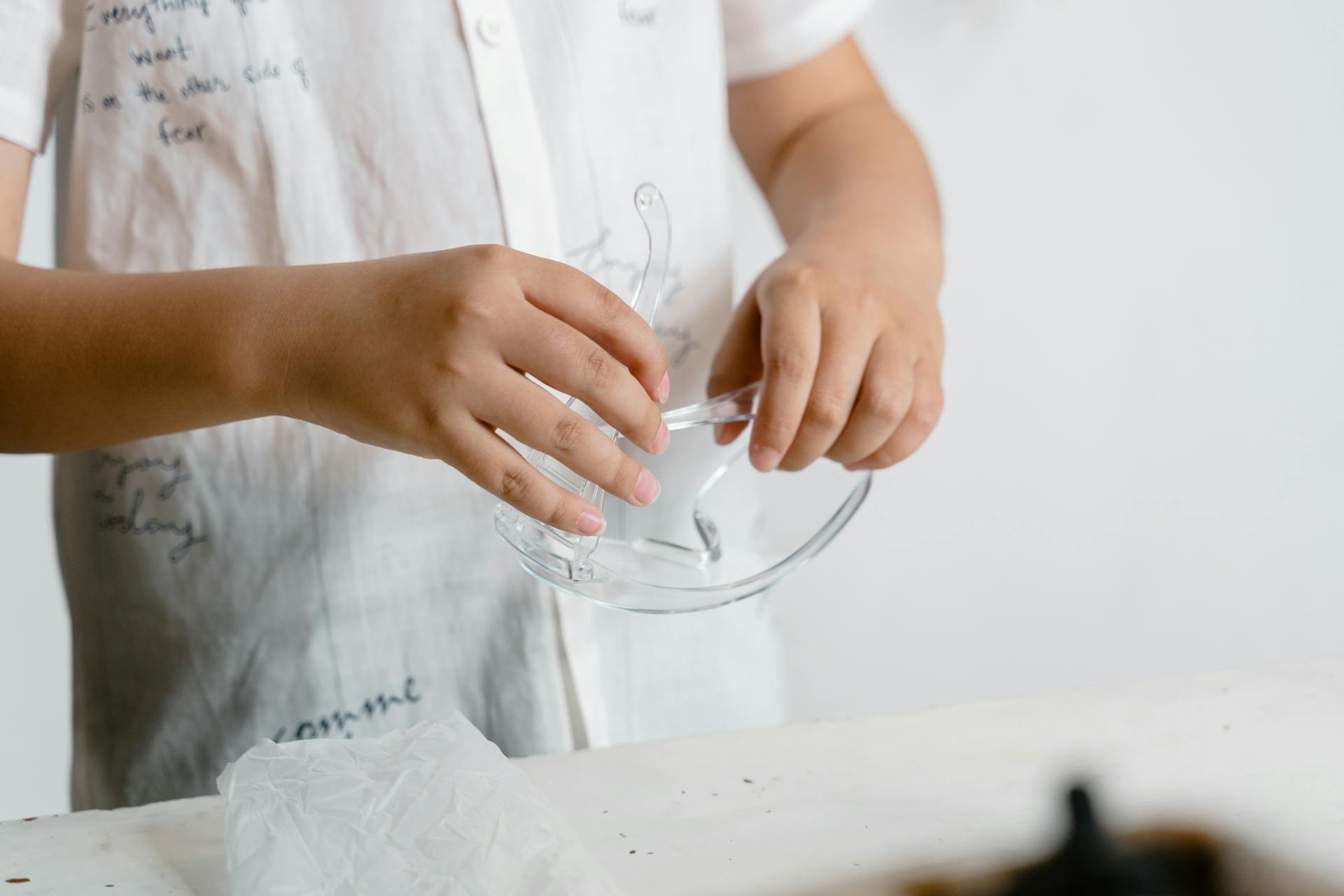 A child carefully holding safety glasses in a close-up photo, emphasizing safety.