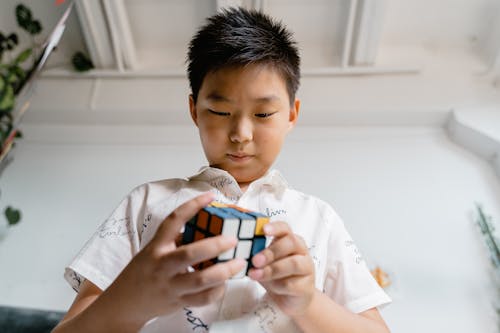 Close-Up Photo of a Boy Playing a Rubik's Cube
