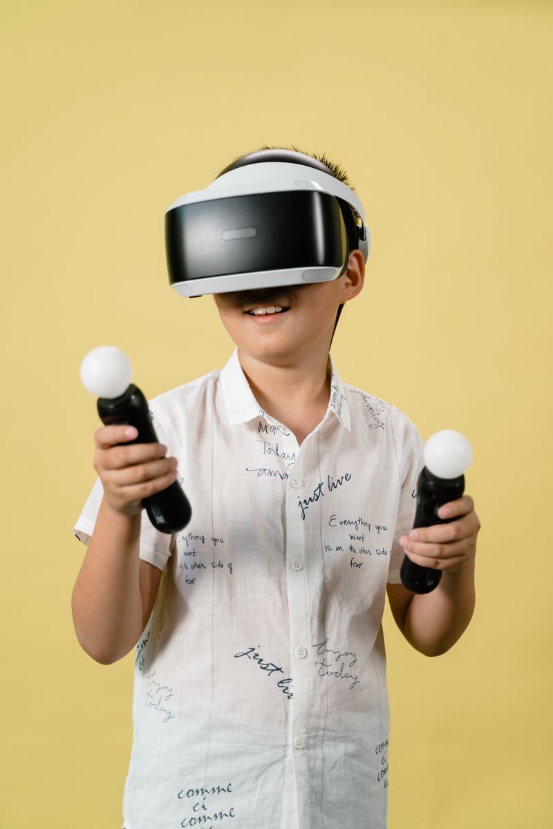 Boy immersed in virtual reality with VR headset and controllers against yellow background.