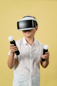 Boy immersed in virtual reality with VR headset and controllers against yellow background.
