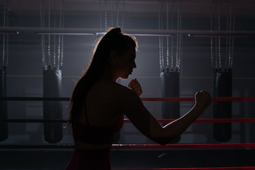 Silhouette of a female boxer in a gym preparing for training. Strong and determined focus.