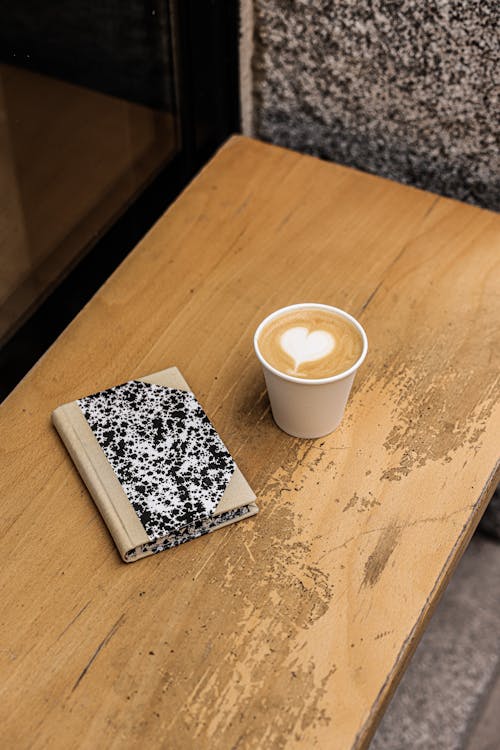 A Coffee Cup and Book on a Wooden Table