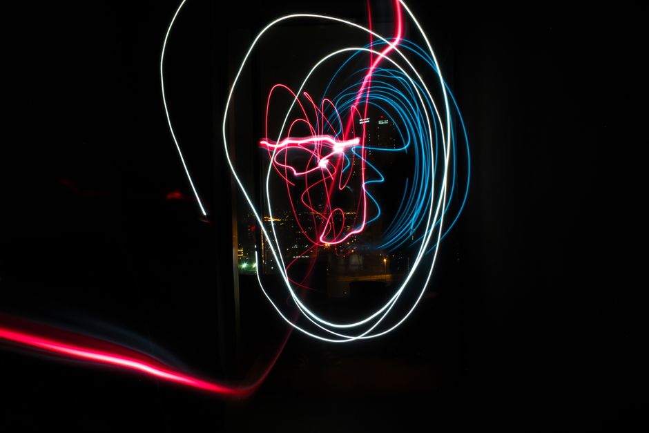 A vibrant display of red and blue light trails against a dark city background.