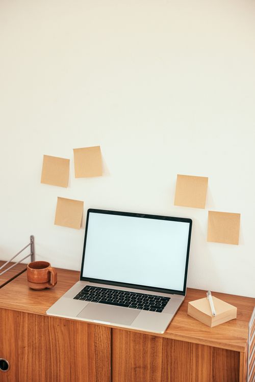 Free Minimalist workspace with laptop and sticky notes on a wooden desk. Stock Photo