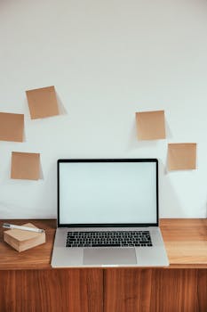 Modern minimalist workspace with a blank laptop screen and sticky notes on a wooden desk.