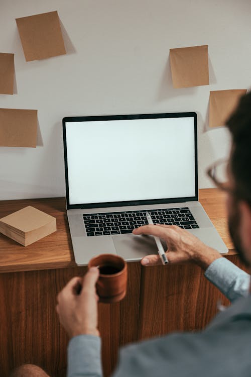 Free A Man Working while Holding a Cup of Coffee Stock Photo