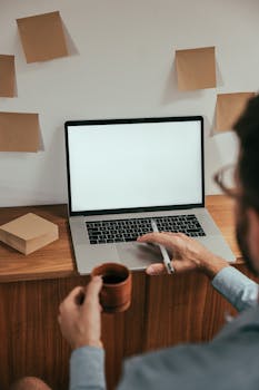 Man working remotely with laptop and coffee in a cozy home workspace.