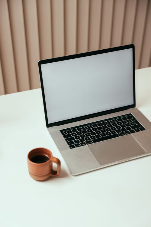 Free A minimalist workspace with a laptop and a cup of coffee on a clean desk, perfect for technology or productivity themes. Stock Photo