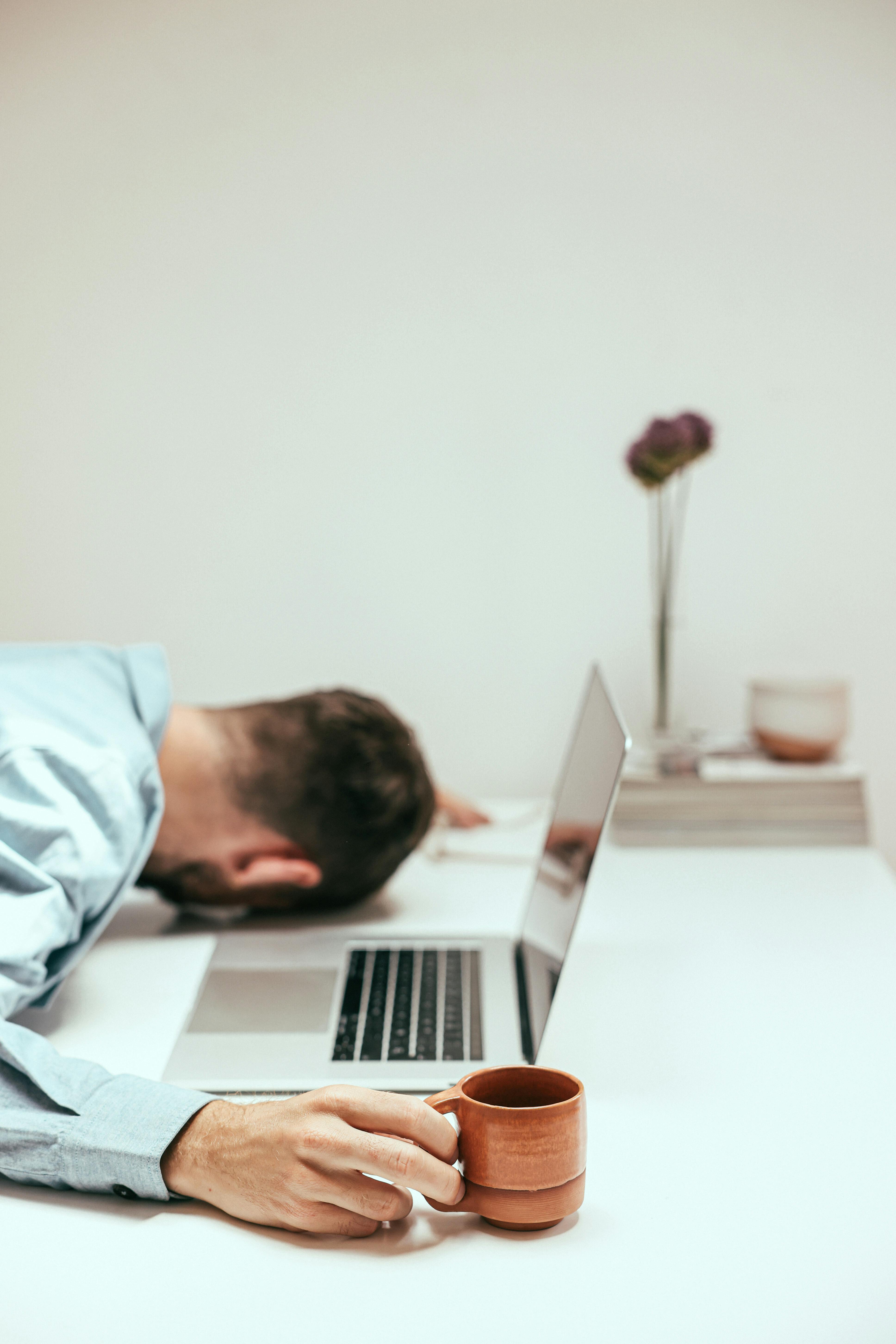 an overworked man holding a cup