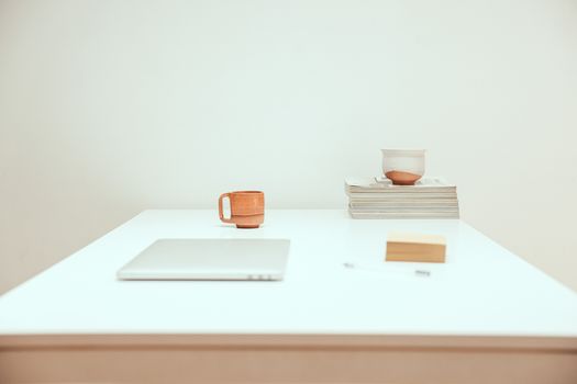 Simple minimalist workspace featuring a laptop, mug, and stacked magazines.