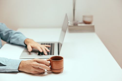 Free A cozy remote work environment featuring a laptop and coffee mug on a minimalist desk. Stock Photo