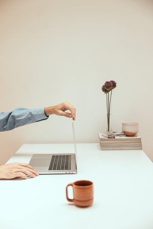 A Person Using a Laptop on White Table