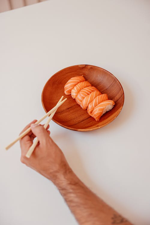 Person Using Chopsticks to Get a Delicious Sushi