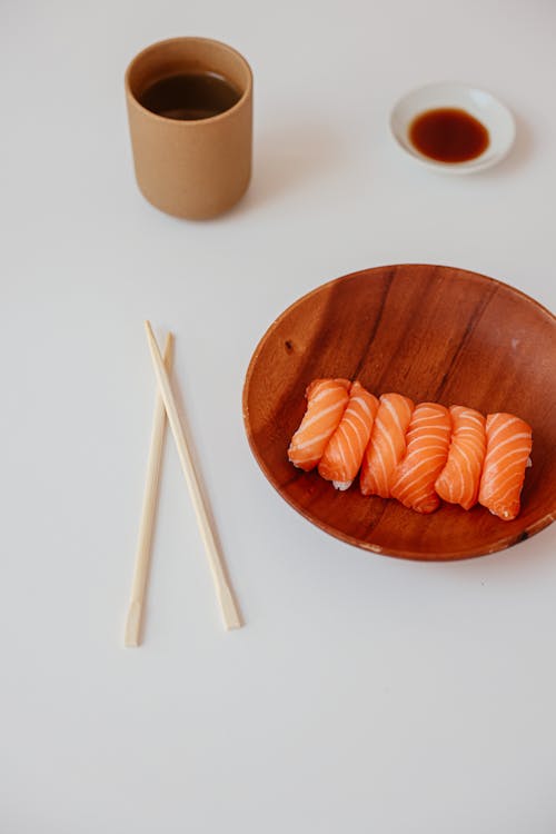 A Delicious Sushi on a Wooden Plate beside a Chopsticks