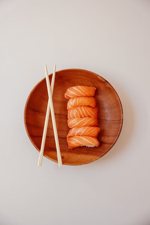 A Delicious Sushi on a Wooden Plate beside a Chopsticks