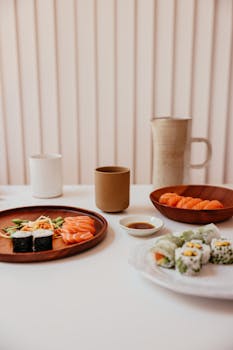 A beautifully arranged sushi meal featuring salmon nigiri, sushi rolls, and soy sauce in a minimalist setting.