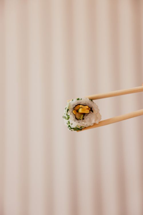 Free Close-up of delicious sushi roll held by chopsticks against a soft background. Stock Photo
