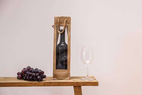 Free A Bottle of Wine Glass Between a Goblet Glass and Grapes o the Table Stock Photo