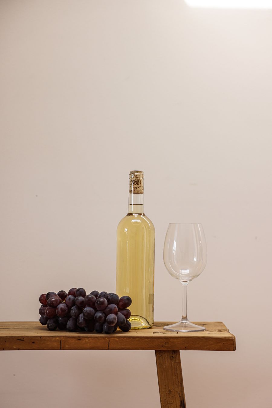 Bottiglia di vino rosso, calice e uva su tavolo di legno