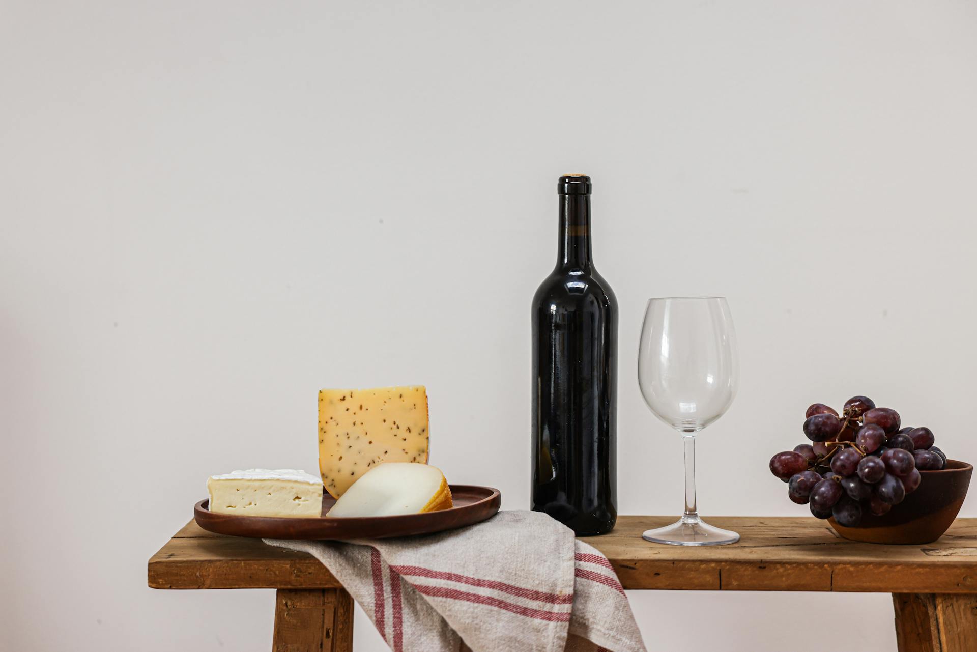 Cheese and Grapes by Wine Bottle on Table