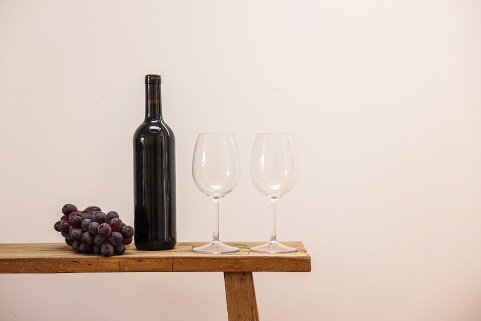 Elegant still life of a wine bottle, grapes, and glasses on a wooden table.