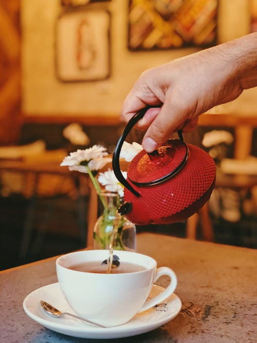 Person Pouring Tea on White Ceramic Cup