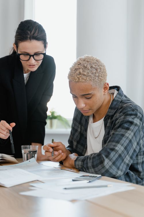 Free Two colleagues engaging in a collaborative work session, reviewing documents at a desk. Stock Photo