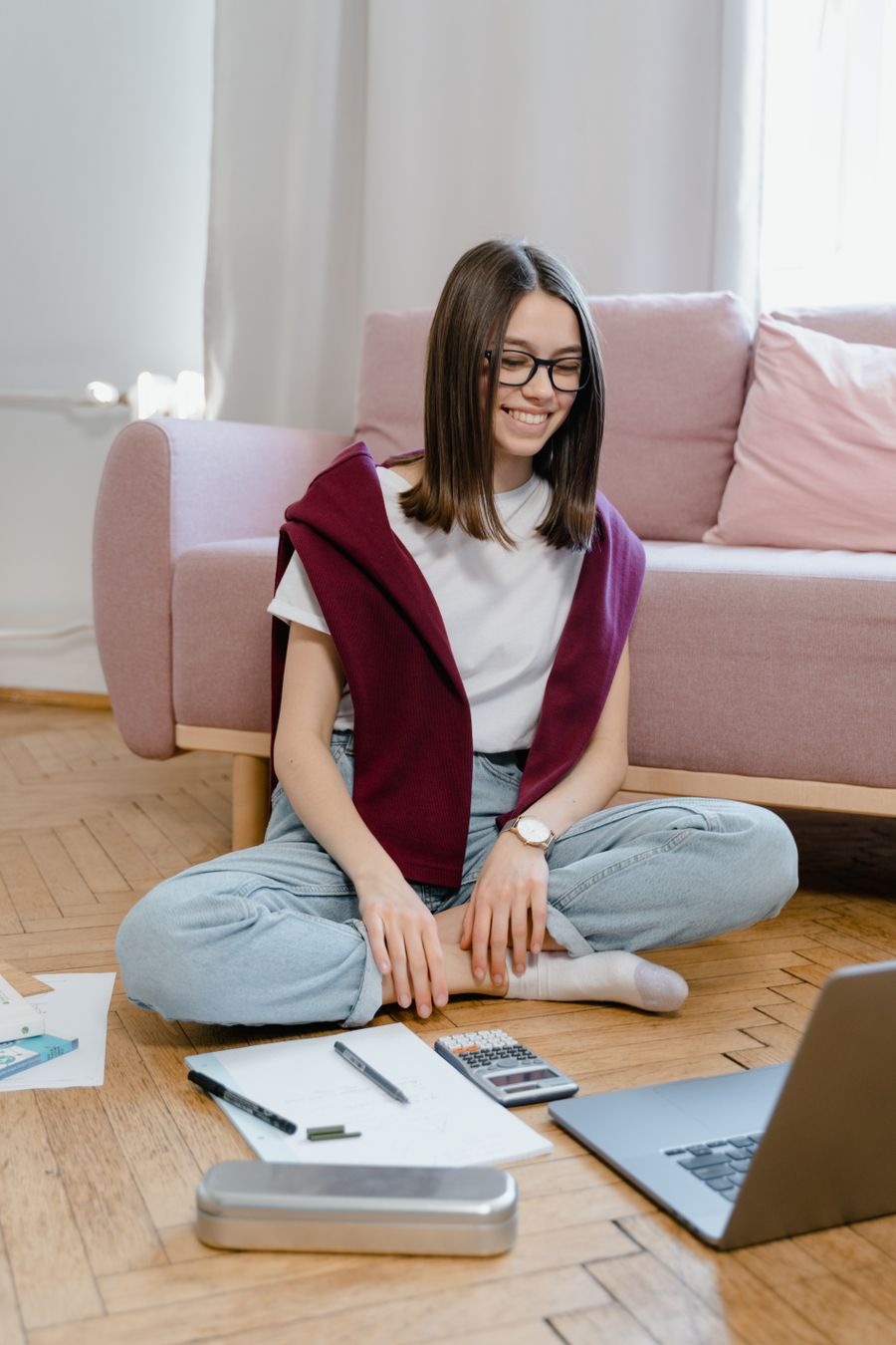 Uśmiechnięta nastolatka w okularach podczas nauki online przy laptopie