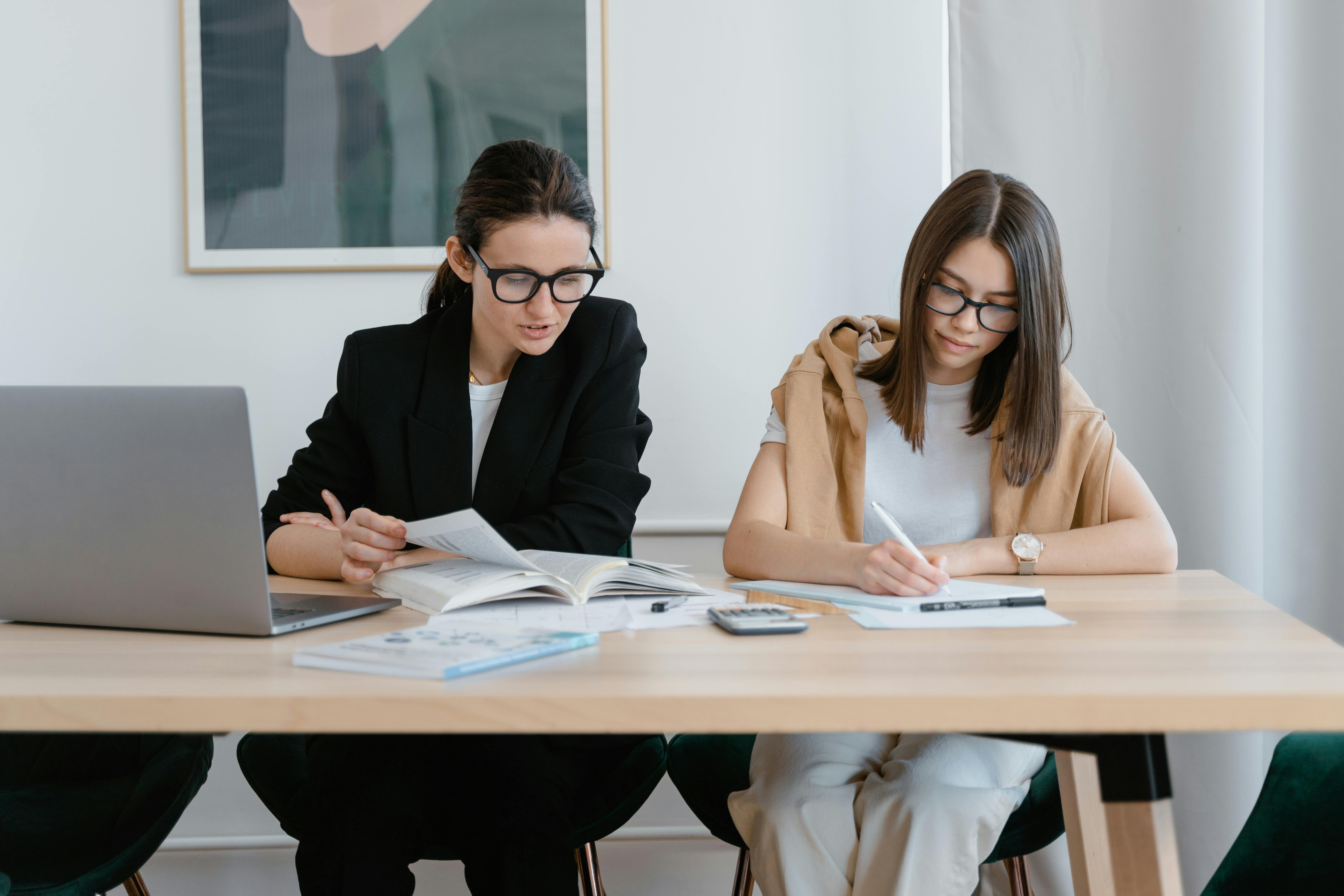 woman in black blazer sitting beside woman in black blazer