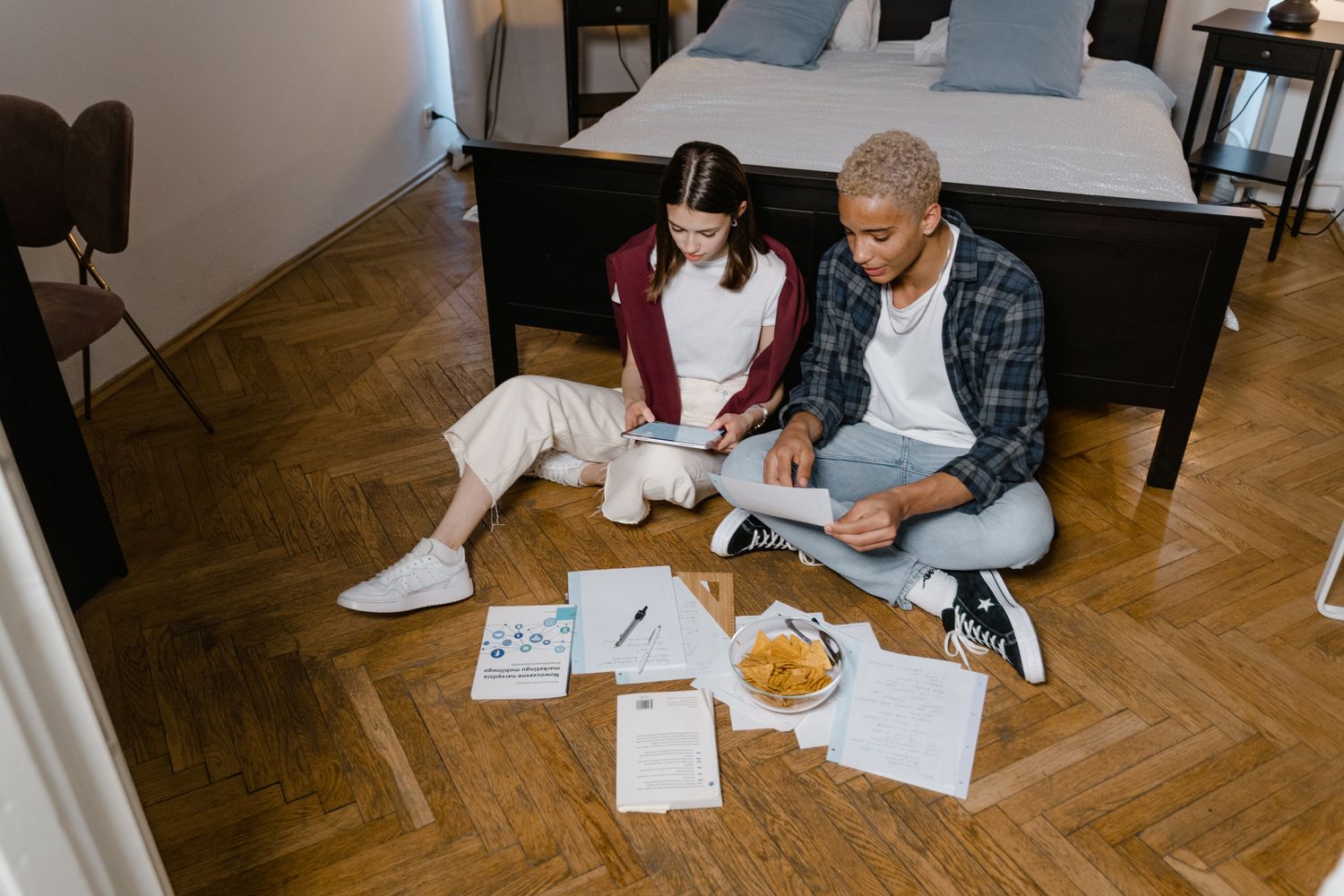 Two young adults studying together indoors, creating a cozy learning atmosphere.