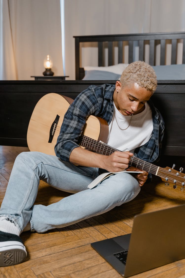 A Young Man Taking An Online Guitar Lesson