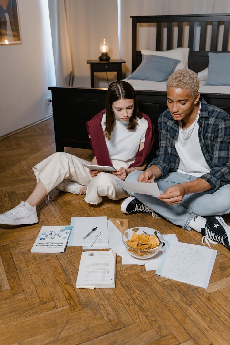 Boy And Girl Sitting On Wooden Floor In The Bedroom