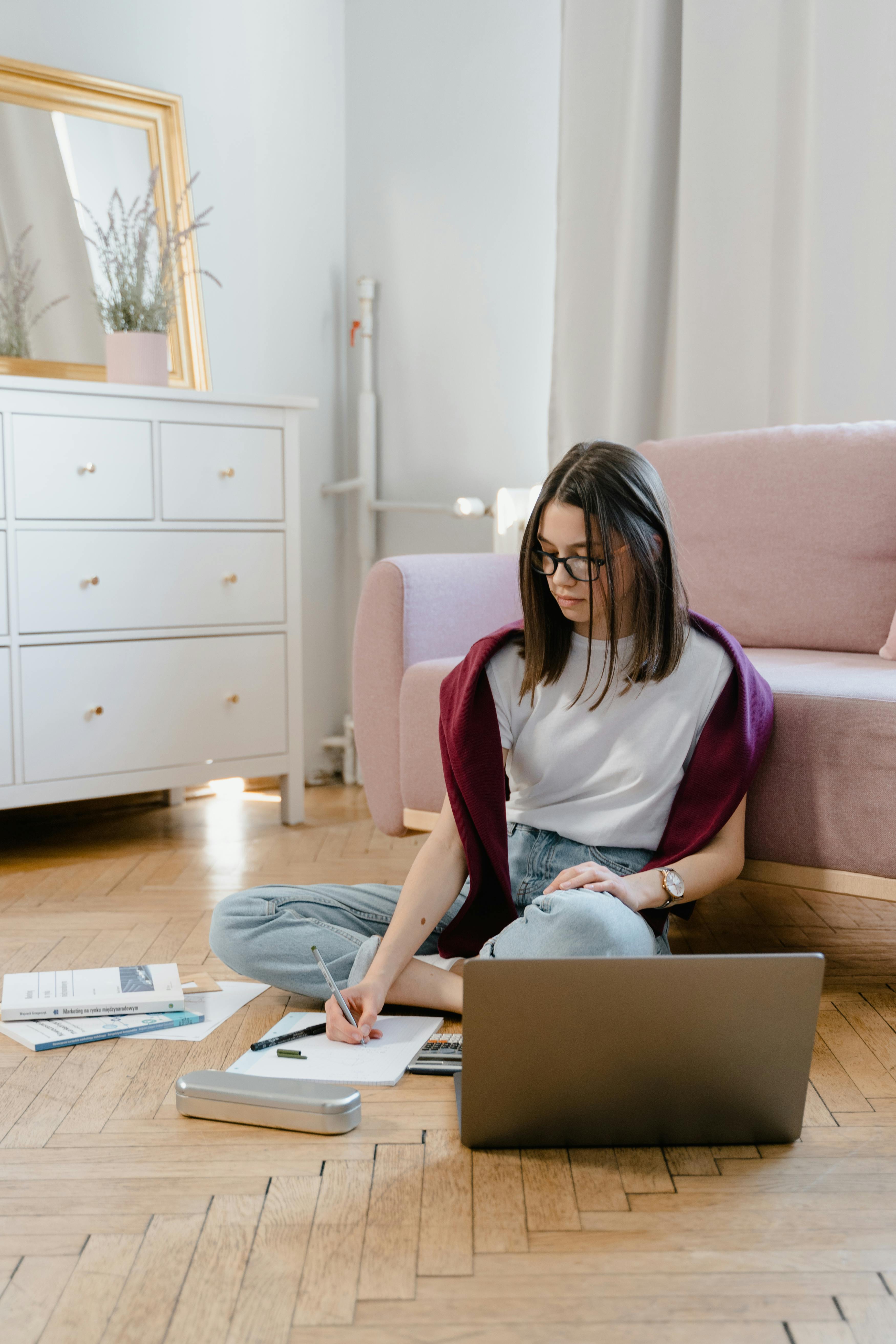 a young woman sitting on the floor while taking an online class