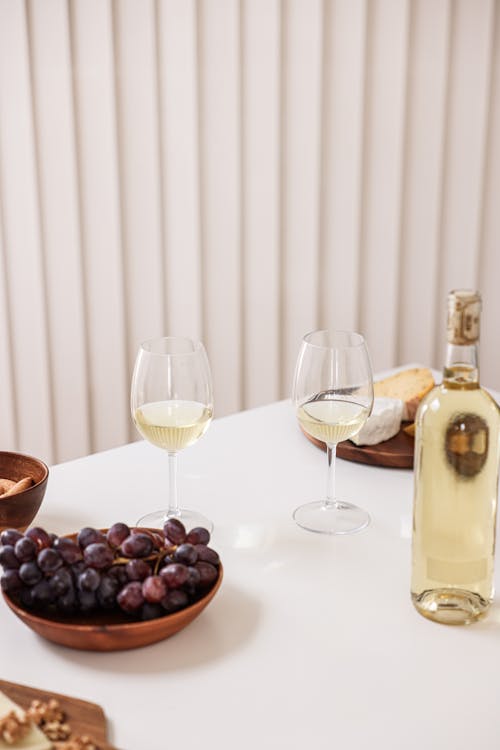 Free Clear Wine Glasses and Bottle Beside a Bowl of Grapes Stock Photo