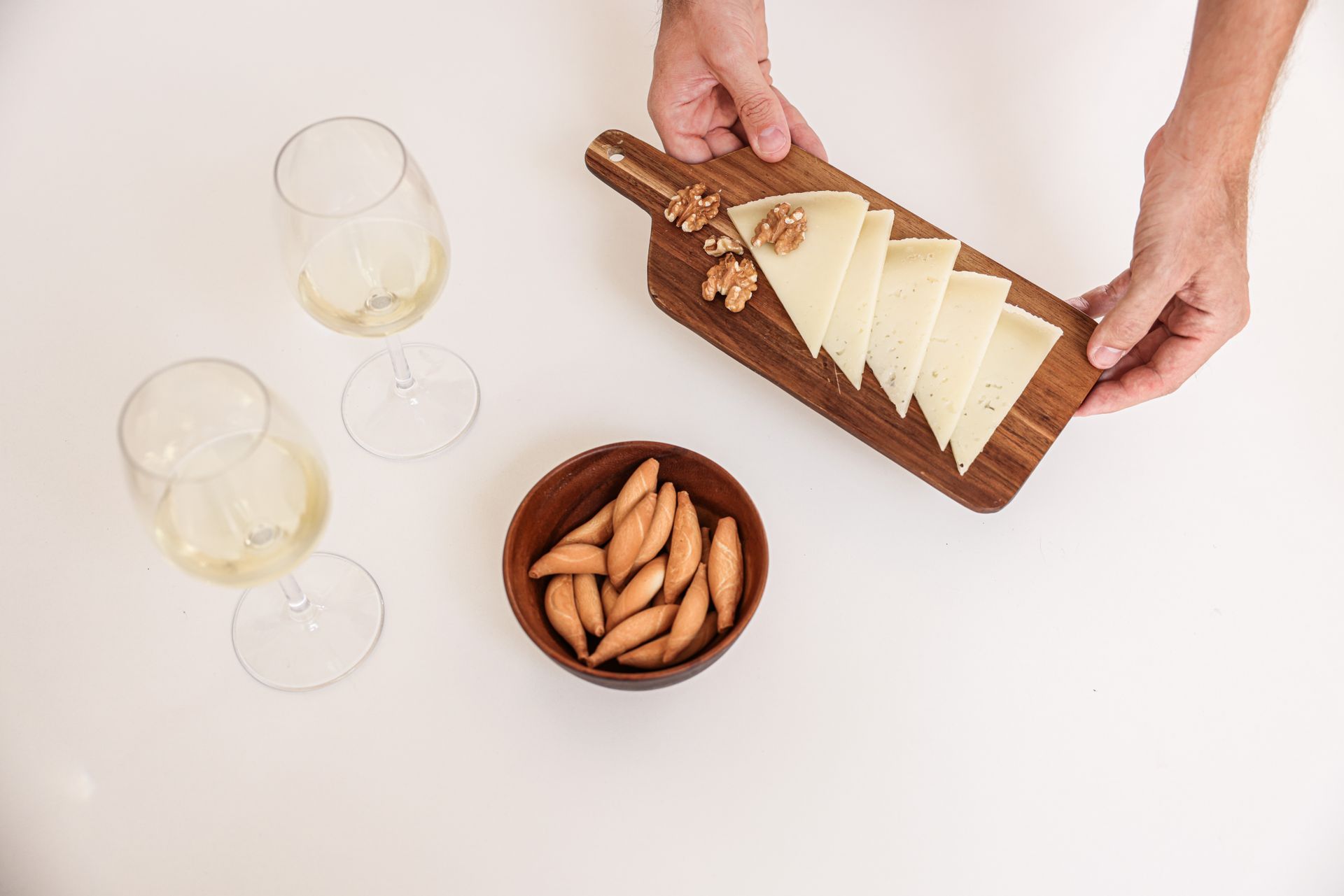 Cheese board with wine glasses and snacks on a white table. Perfect for entertaining.