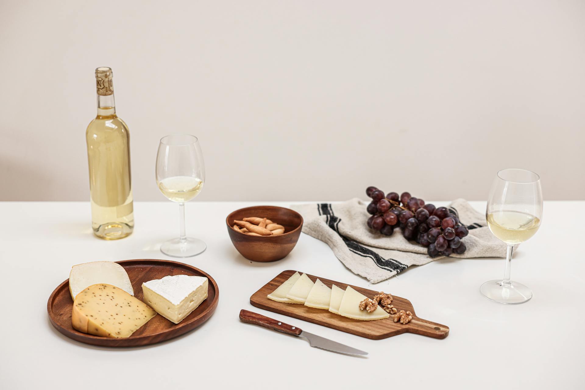 A sophisticated still life of assorted cheeses, grapes, and wine for a perfect tasting event.