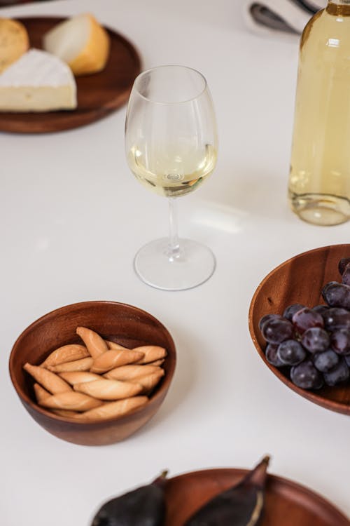 Free A Wine Glass Near the Wooden Bowls with Food Stock Photo
