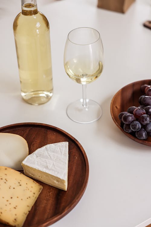 Free A Wine Glass Near the Wooden Plate with Cheese Stock Photo
