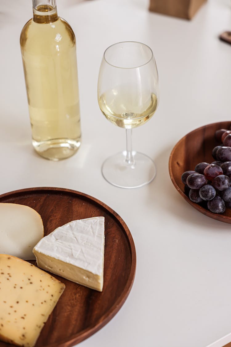 A Wine Glass Near The Wooden Plate With Cheese