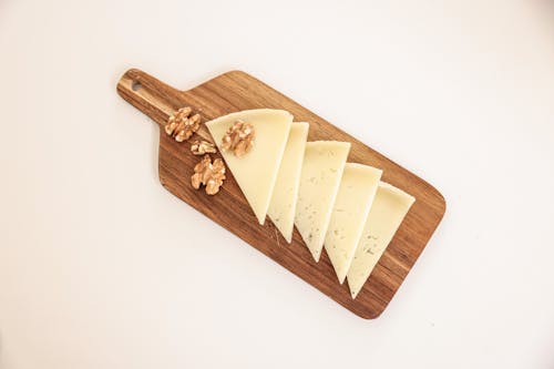 A Sliced Cheese and Walnuts on a Wooden Board