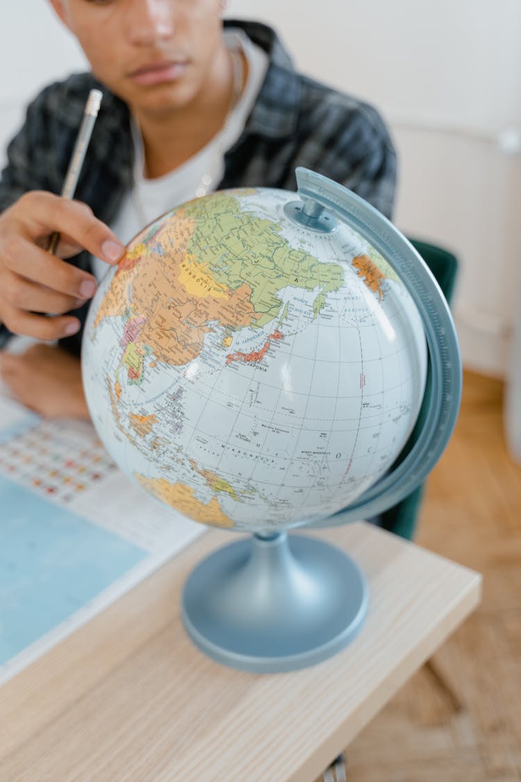 Close-Up Photo Of A Student Studying The World Map