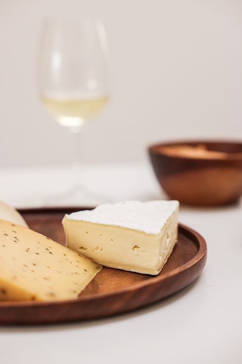 Free Close-up of assorted cheeses with a glass of white wine, creating a perfect pairing. Stock Photo