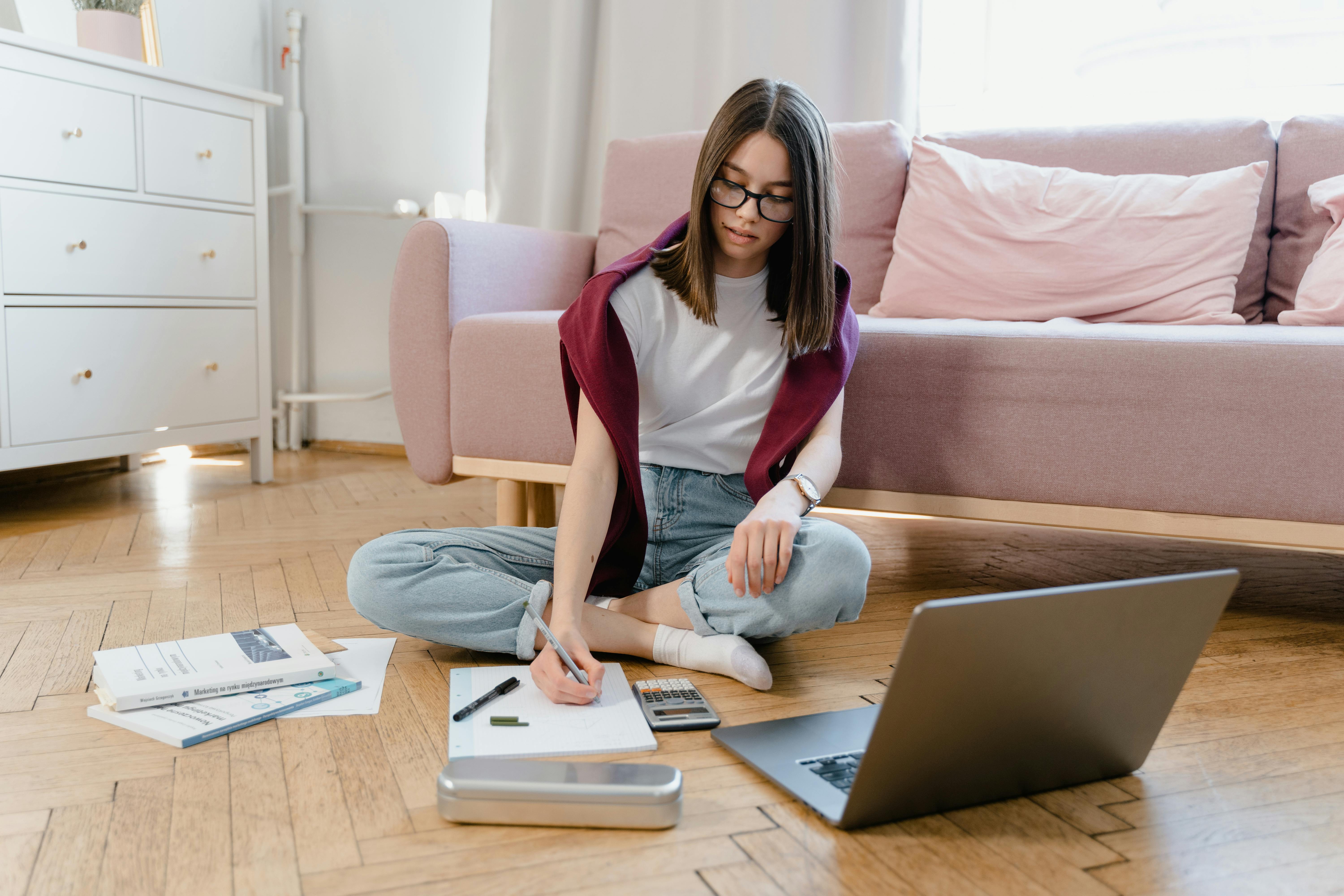 a young woman sitting on the floor while taking an online class