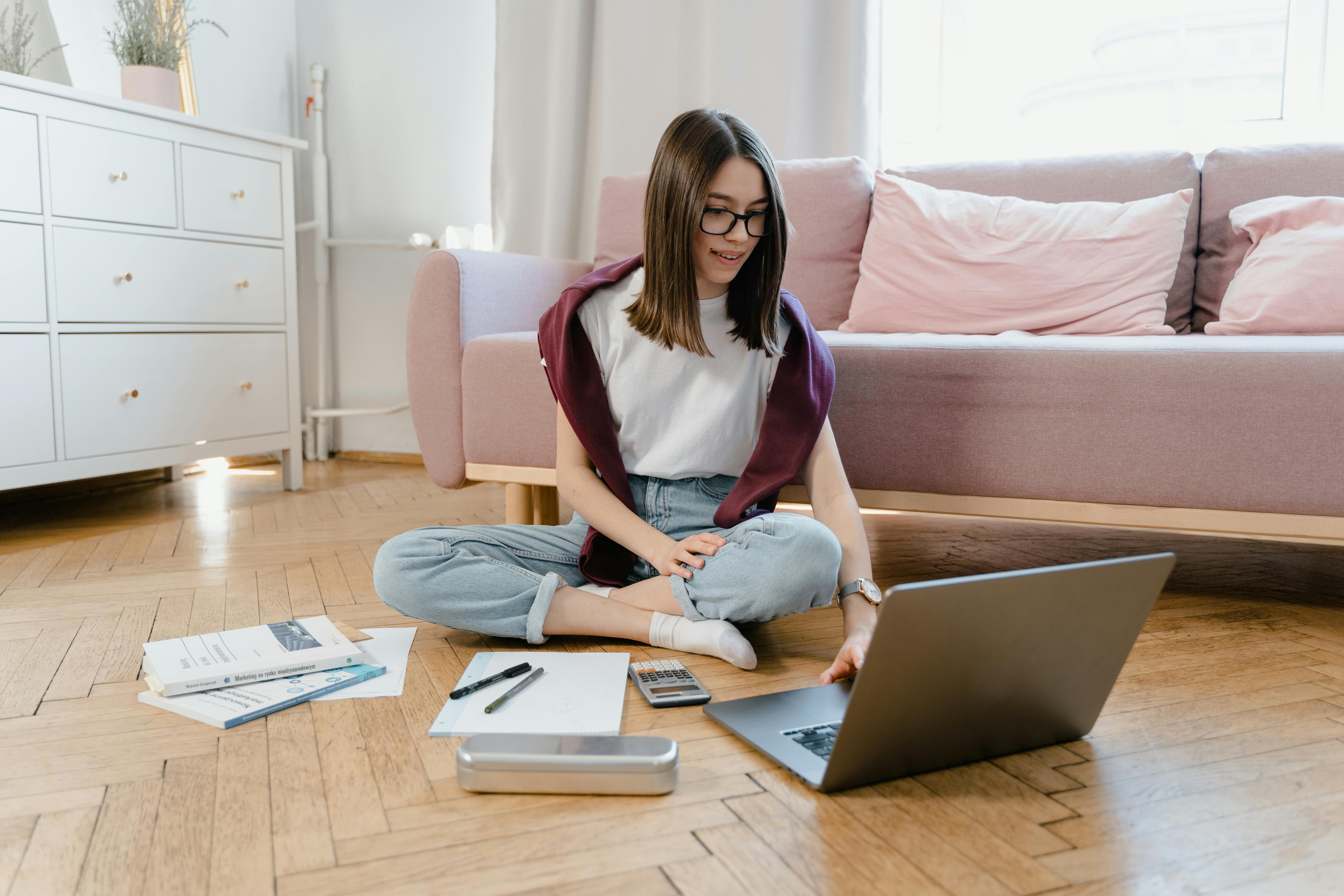 a young woman sitting on the floor while taking an online class