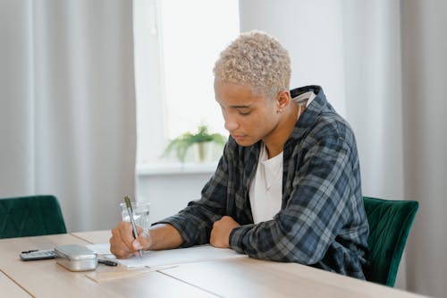 A Young Man Doing his Homework on a Table