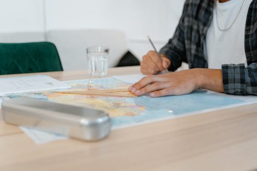 A Student Taking Notes While Looking at a World Map