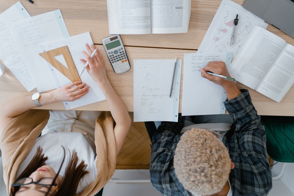 本、計算機、幾何学ツールを使って数学を勉強している二人の学生の上からの視点。