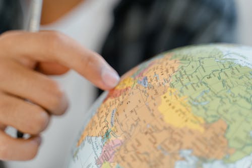 Close-up of a Person Pointing at a Globe